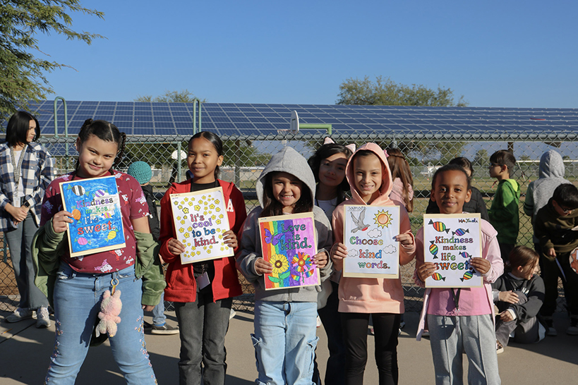 Students proudly hold up their drawings